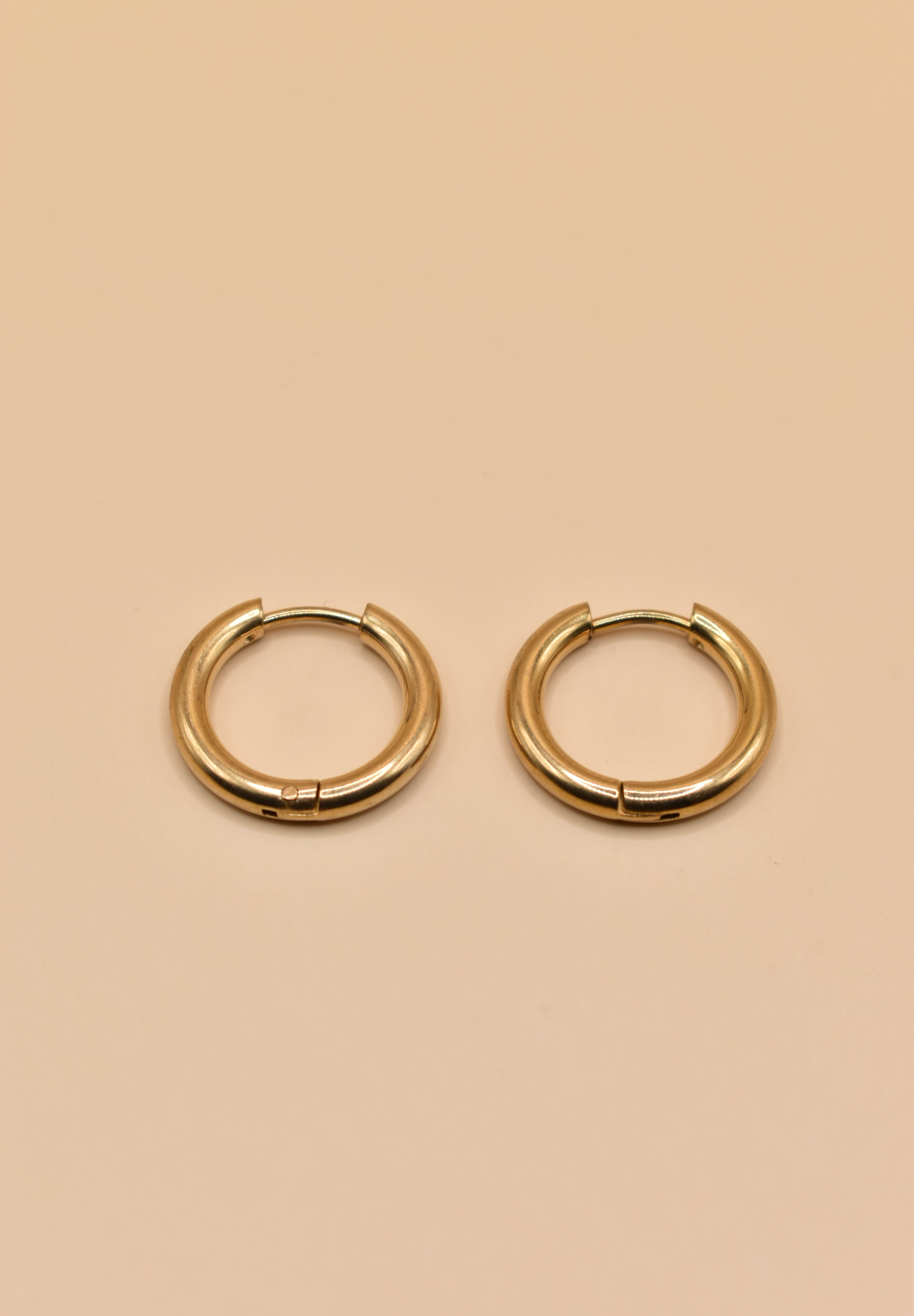Gold circle huggie hoop earrings on white background