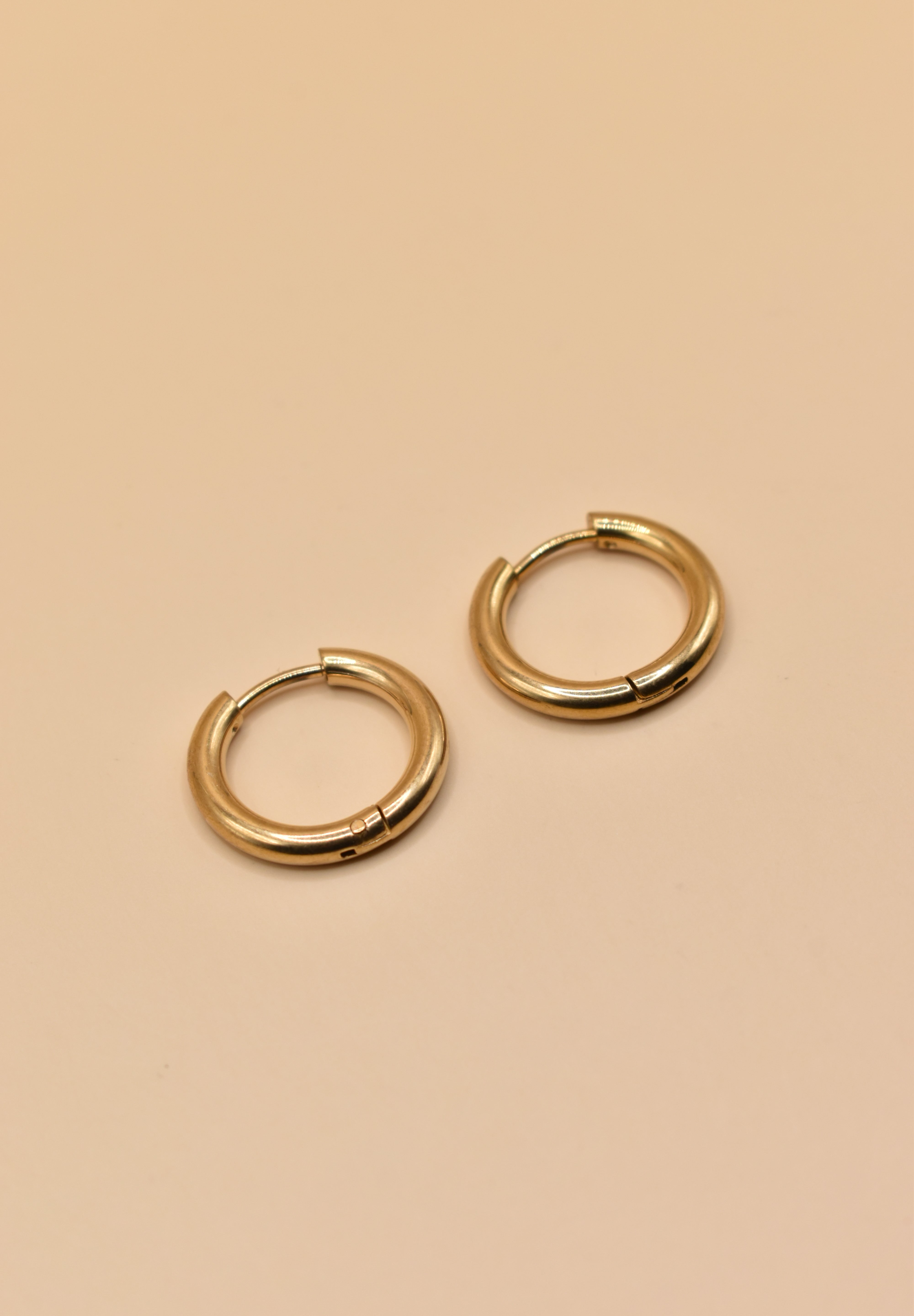 Gold circle huggie hoop earrings on white background