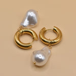 Gold huggies earrings with pearl drop on white background
