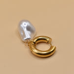 Gold huggies earrings with pearl drop on white background