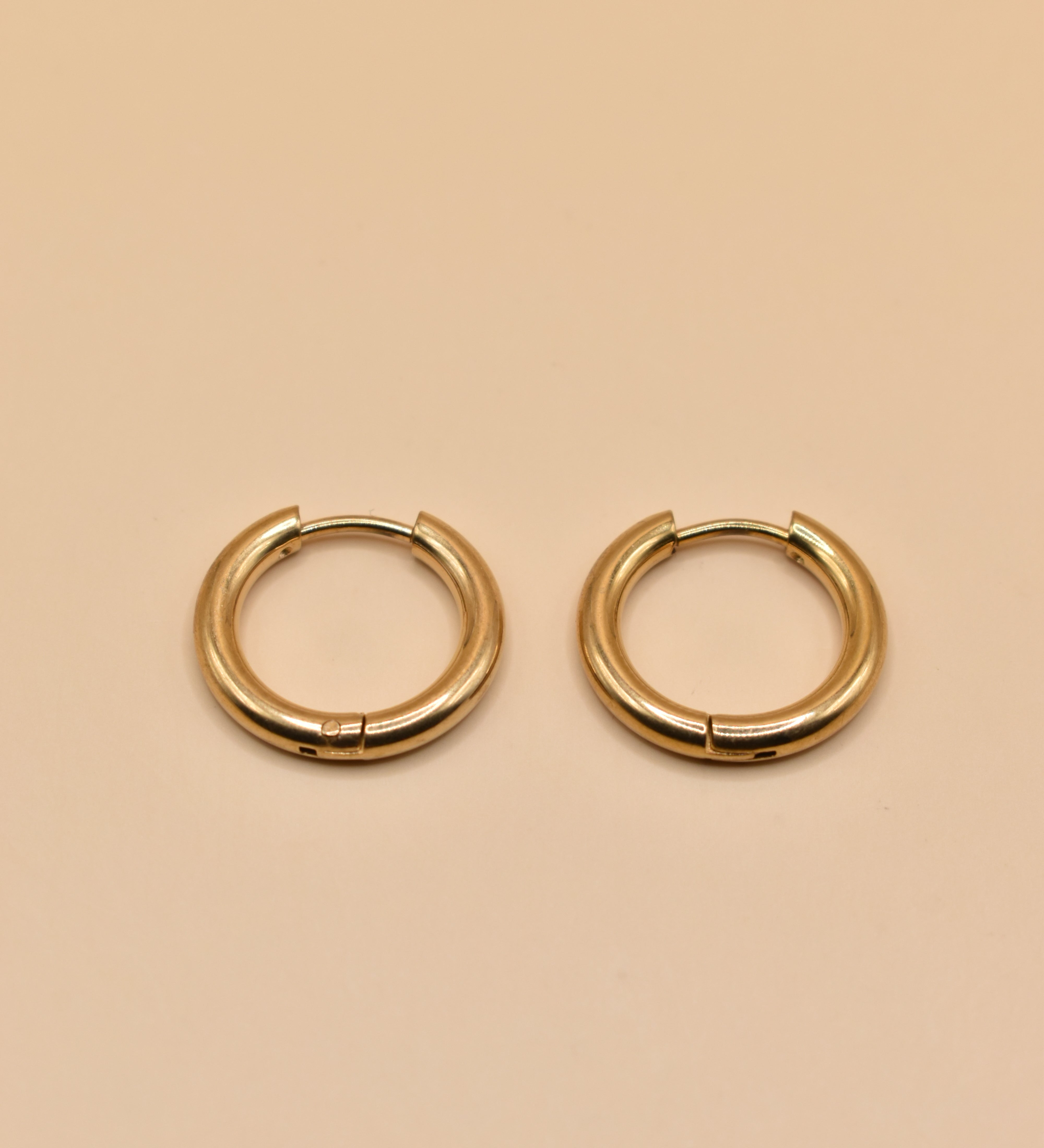 Gold circle huggie hoop earrings on white background
