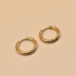 Gold circle huggie hoop earrings on white background