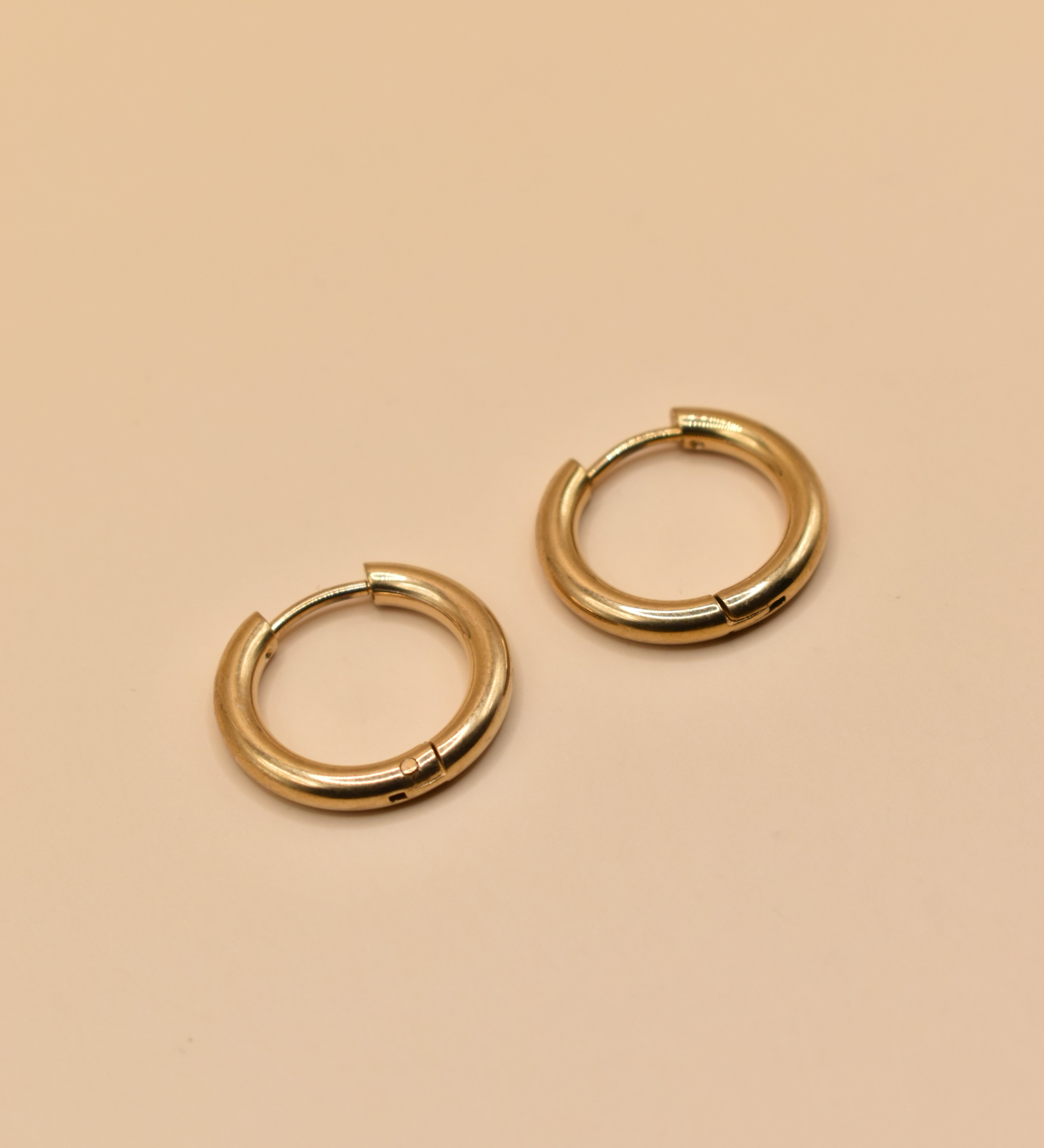 Gold circle huggie hoop earrings on white background