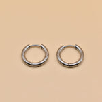 Gold circle huggie hoop earrings on white background